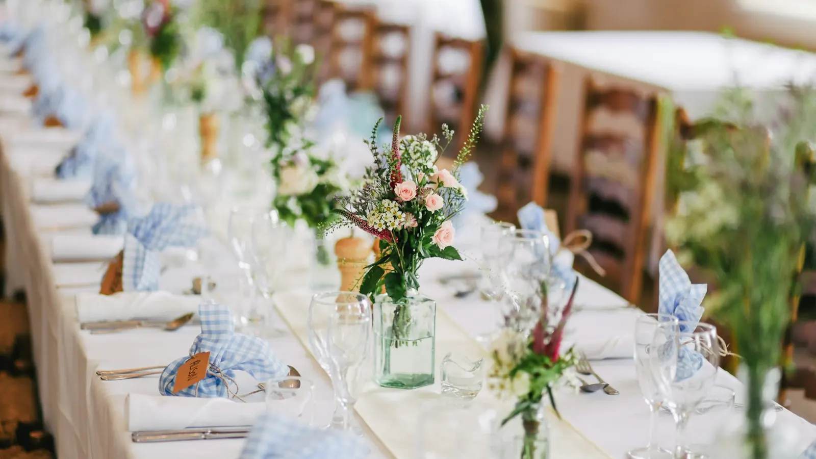 Mesa de casamento decorada com flores, taças e guardanapos azuis